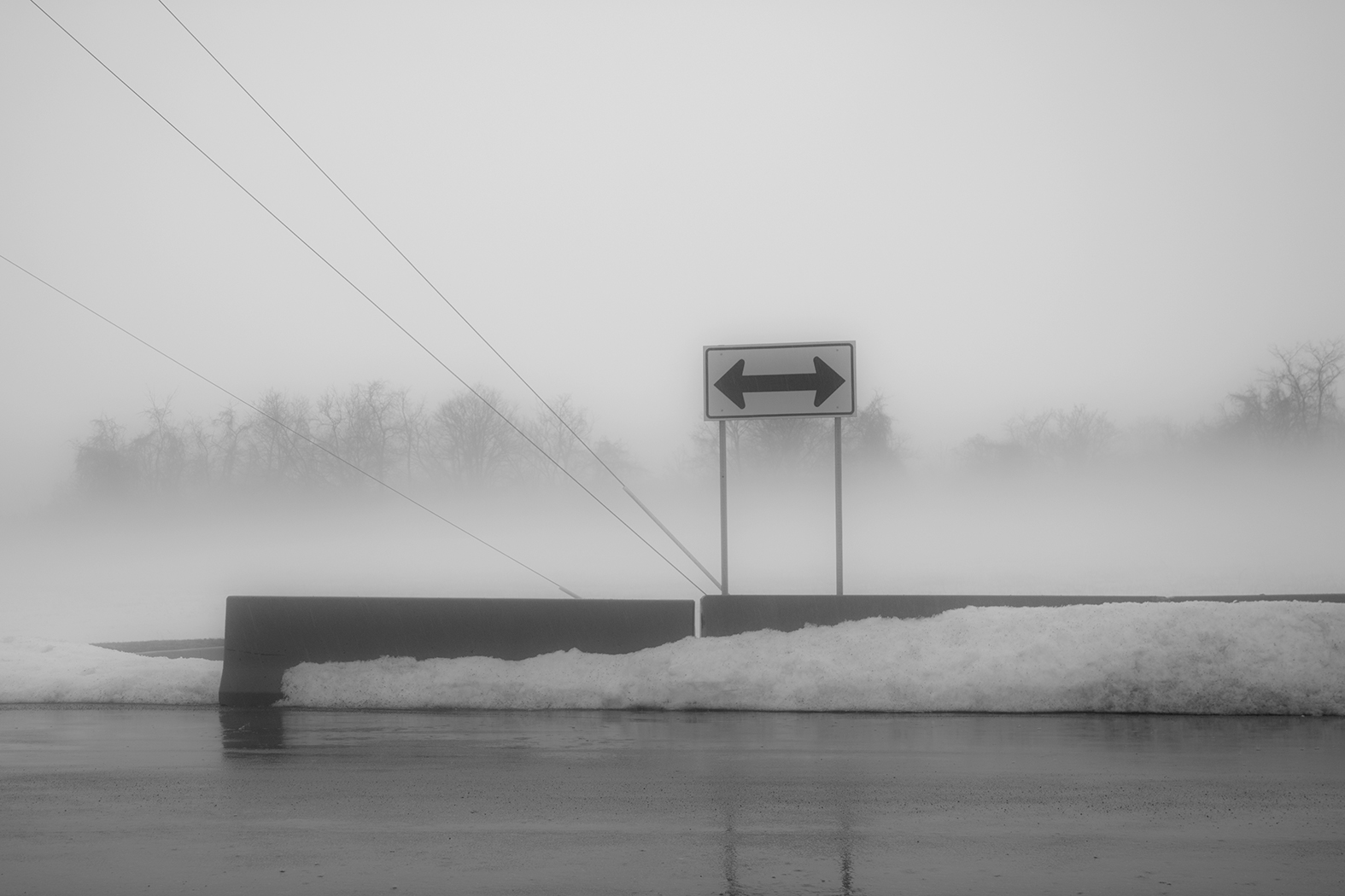 A sign on a foggy snowy day